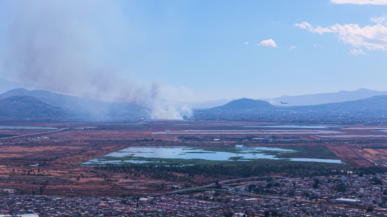 Riprese con drone sul nord di Città del Messico con un incendio boschivo lontano visibile.
