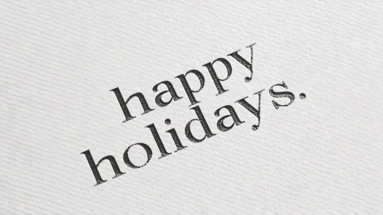 Rotating printed greeting shifting on textured paper with frames advancing, showing happy holidays