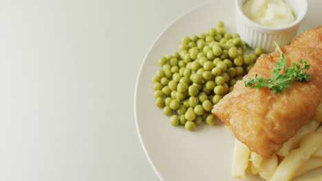 video of fish, chips and peas on plate with dip, with copy space on white background