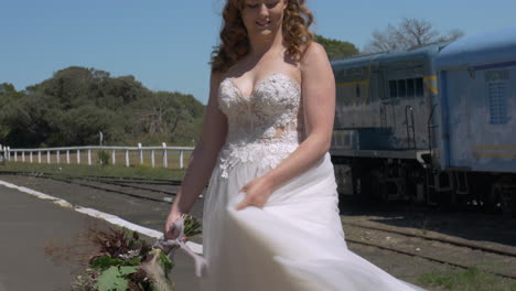 la novia pelirroja gira en la estación de tren, se inclina hacia arriba