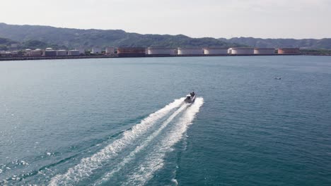 Aerial-drone-follows-motorboat-at-Wakayama-Sea-Japanese-Island-Landscape-skyline-at-daylight,-travel-destination-in-Japan-Asia,-sailing