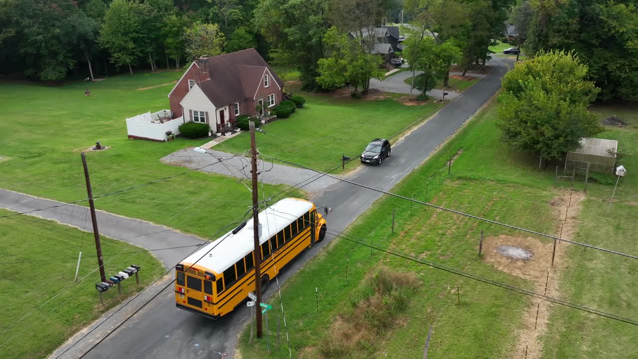 Aerial tracking shot of yellow school bus arriving street in american neighborhood. Transport for pupils and students. waving flag of usa.