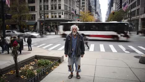 a man in casual clothing stands at a busy intersection in a city as cars and buses rush by. the autumn foliage adds color to the scene, creating a vibrant urban atmosphere.