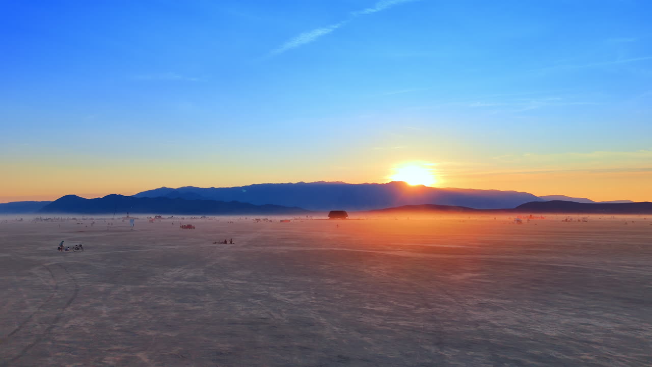 Nevada, USA, 14 August 2025: Cyclist rides across playa at sunset during Burning Man festival.. A lone cyclist moves across the desert as the sun sets