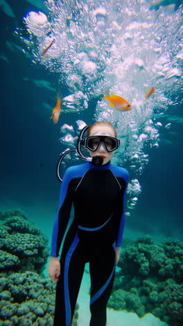 young person scuba diving or snorkeling in blue ocean with bubbles and marine life