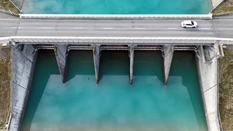 drone footage captures vehicles crossing a bridge over turquoise waters in lake tekapo, new zealand, highlighting serene landscapes and infrastructure