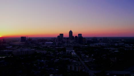 dramatic silhouette of downtown indianapolis against a vibrant, colorful twilight sky at sunset.