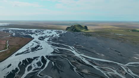 survolant la rivière tressée avec le lit noir du sud de l'islande