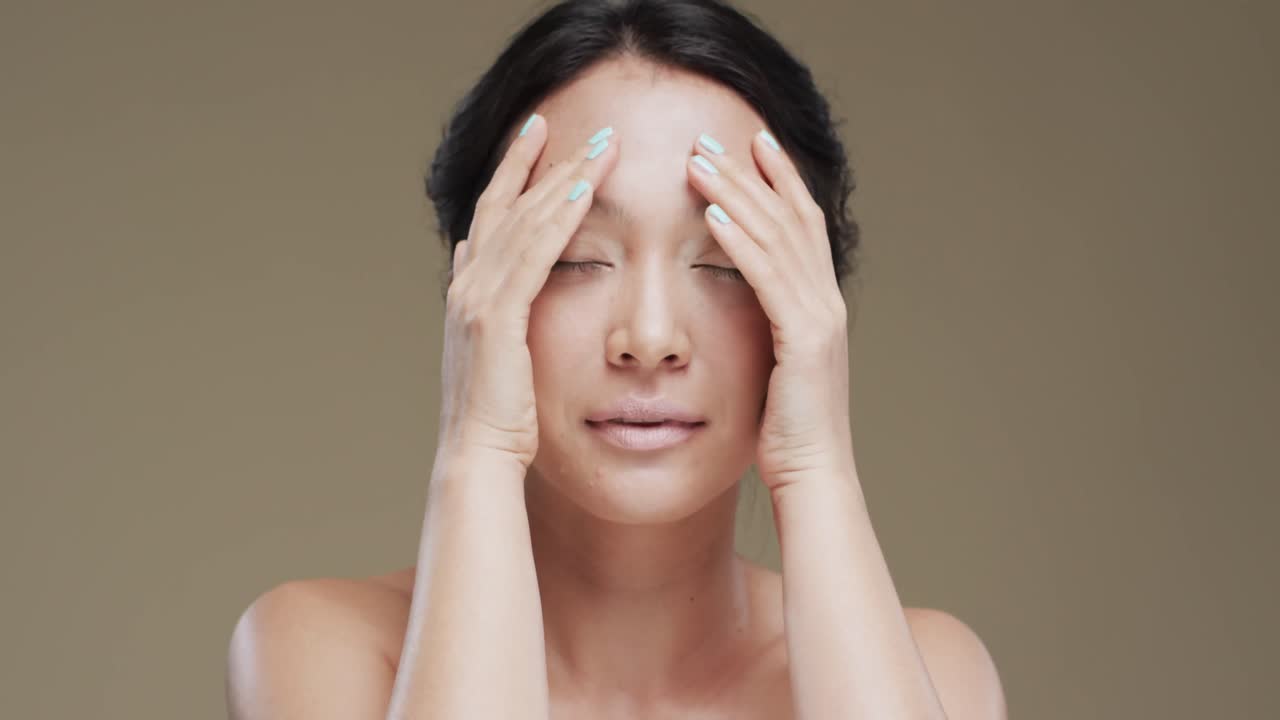 베이지색 배경에 어두운 머리카락을 가진 행복한 아시아 여성, 슬로우 모션