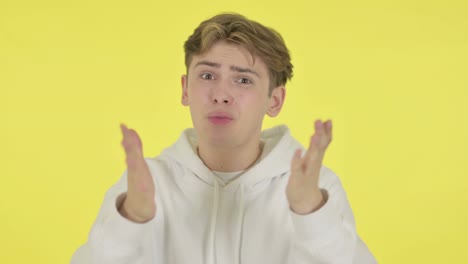 young man fighting, arguing on yellow background