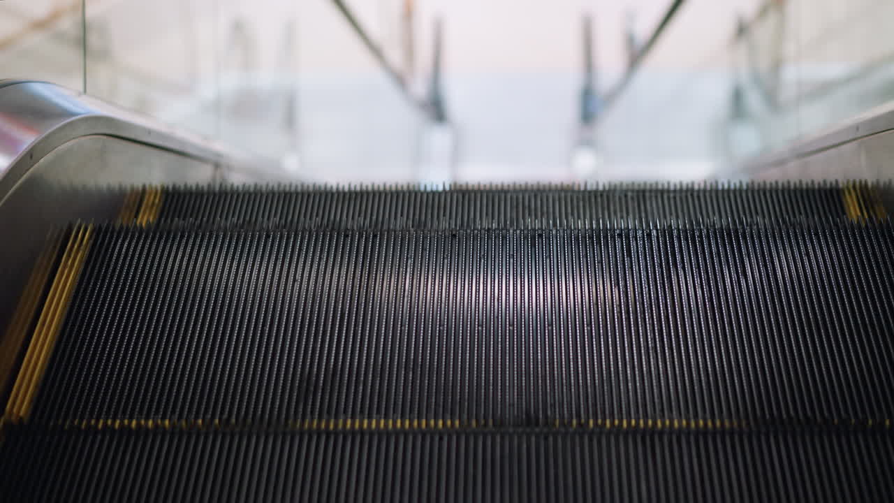 Close up detail of moving escalator steps with black grooves and yellow edges inside shopping mall, showing transport, modern architecture, technology, and everyday lifestyle environment indoors