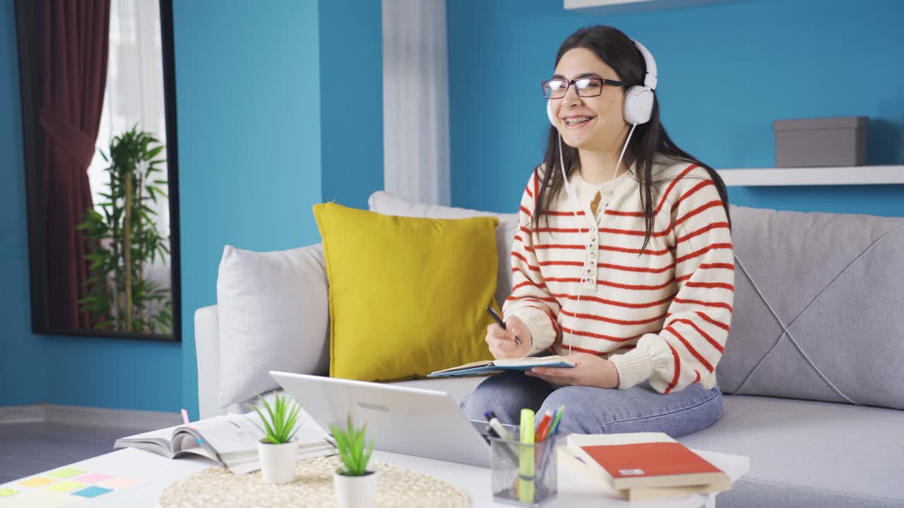 유쾌하고 유쾌한 젊은 여자가 집에서 공부하고 있습니다.