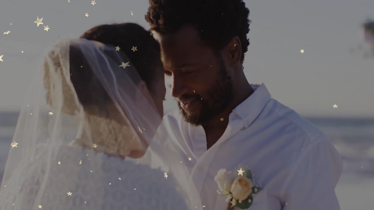 Lo sposo che solleva il velo per rivelare il volto della sposa e avvicina le fronti sotto coriandoli a forma di stella per il matrimonio.