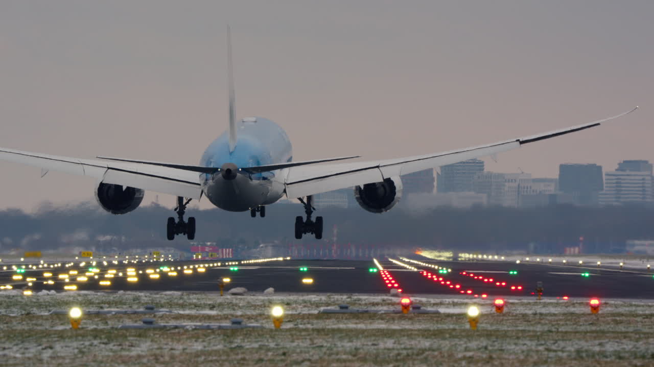 Gran avión de pasajeros aterrizando en una pista de aeropuerto iluminada