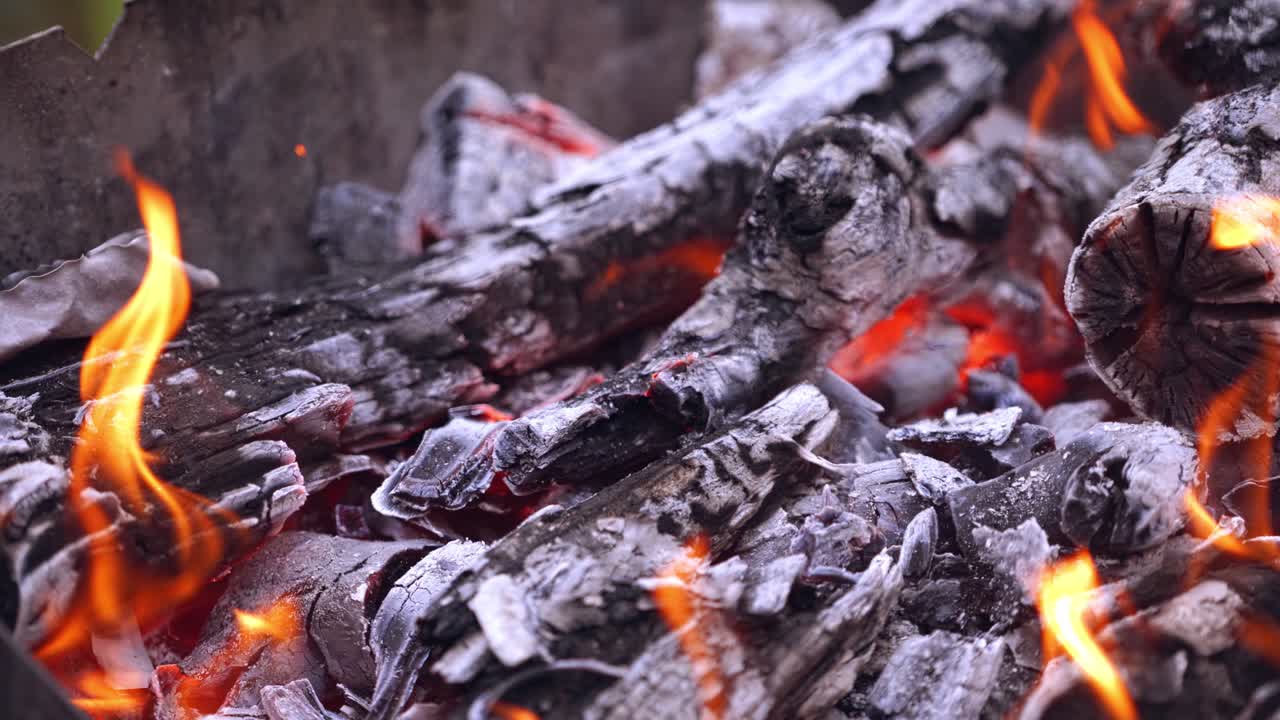 Close-up of hot firewood glowing and burning. Embers of a burnt-out campfire. Wood burning up.