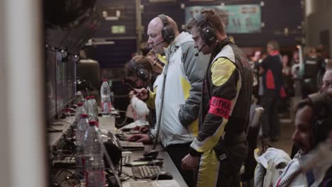 engineers and mechanics race car team looking at race data in garage box paddock on monitors at night during the adac nurburgring twentyfour hour race.