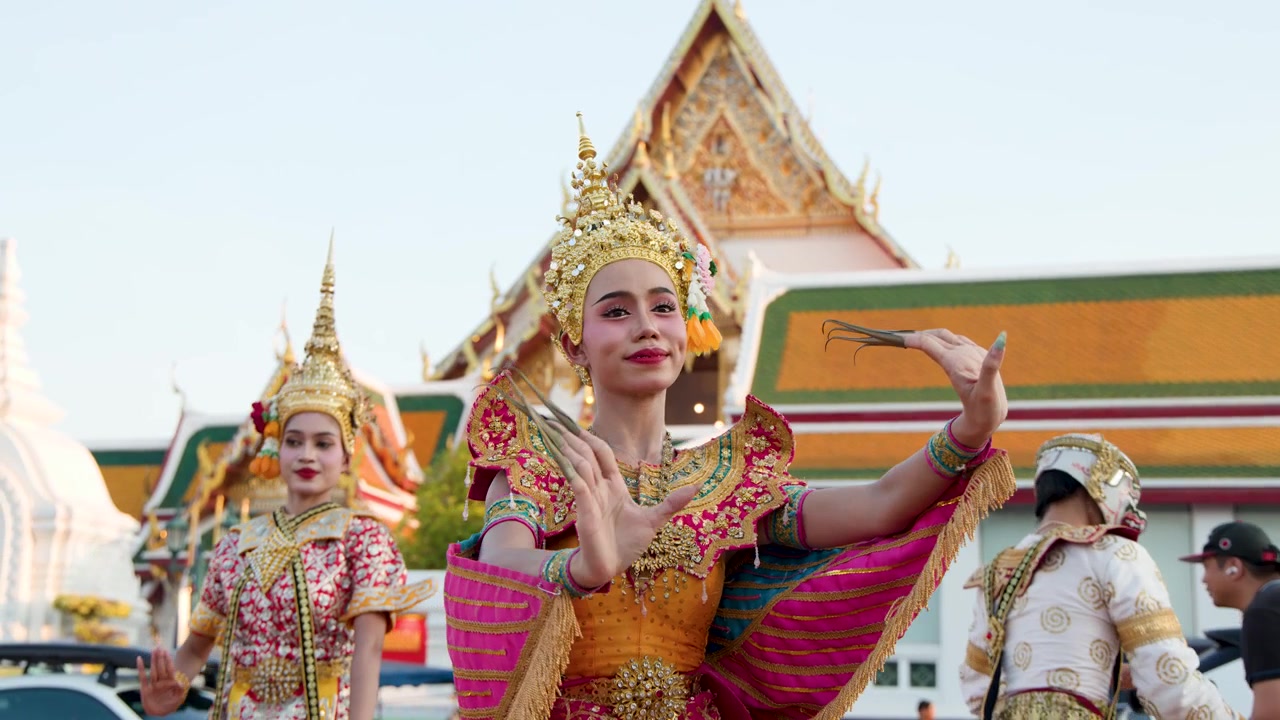 Danzatrici thailandesi ornate eseguono movimenti tradizionali Khon Manohra fuori da un complesso di templi storici di Bangkok