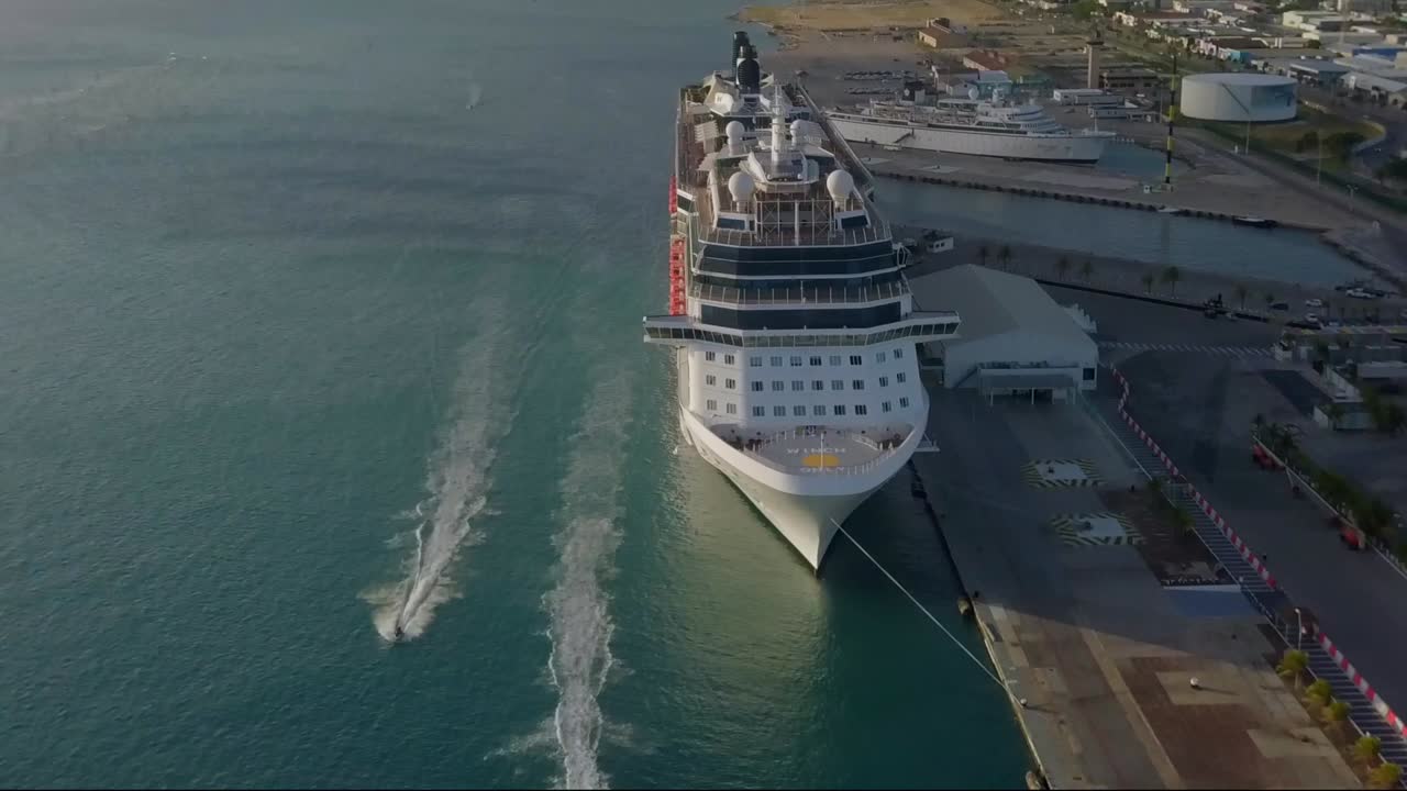 Aerial view of two jet skies sailing in front of a cruise ship and the camera panning down to get a overview of the jet skies sailing by