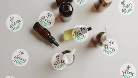 animation of go green text and logos, over beauty products and essential oils on beige background