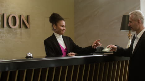 recepcionista recibiendo un pasaporte de un invitado