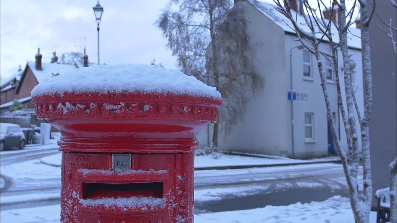 A red postbox covered in snow in a small village. Shot in Northern Ireland.