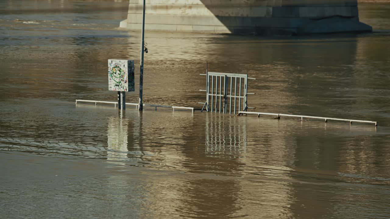 partially submerged fence and utility box amid rising waters during Budapest Flood 2024