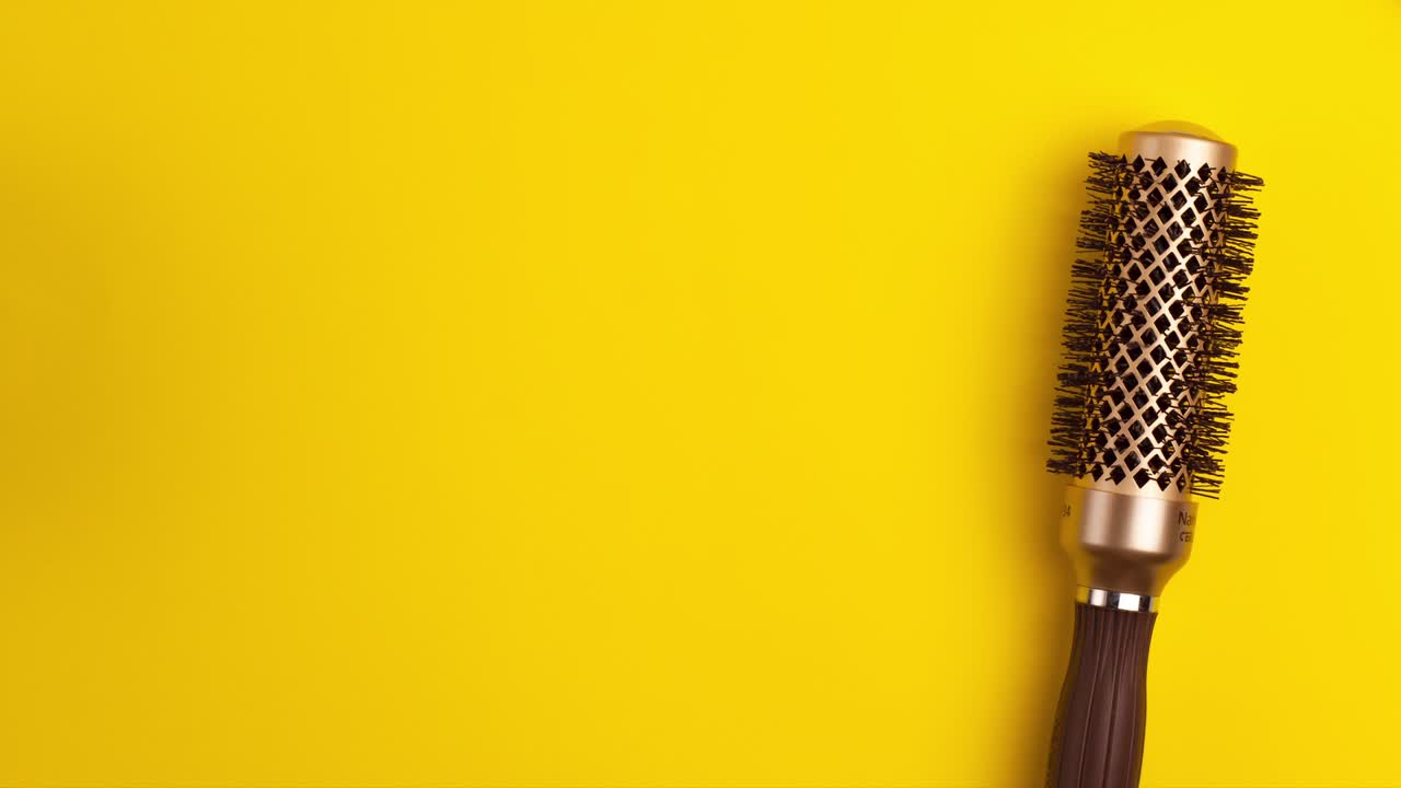 스 모션 애니메이션 템플릿은 황금의 평평한 층, 스타일링을위한 둥근 머리카락 브러쉬, 노란색 배경에 앞뒤로 흔들리는, 복사 공간과 함께 헤어드레스 미용실 장비 개념.