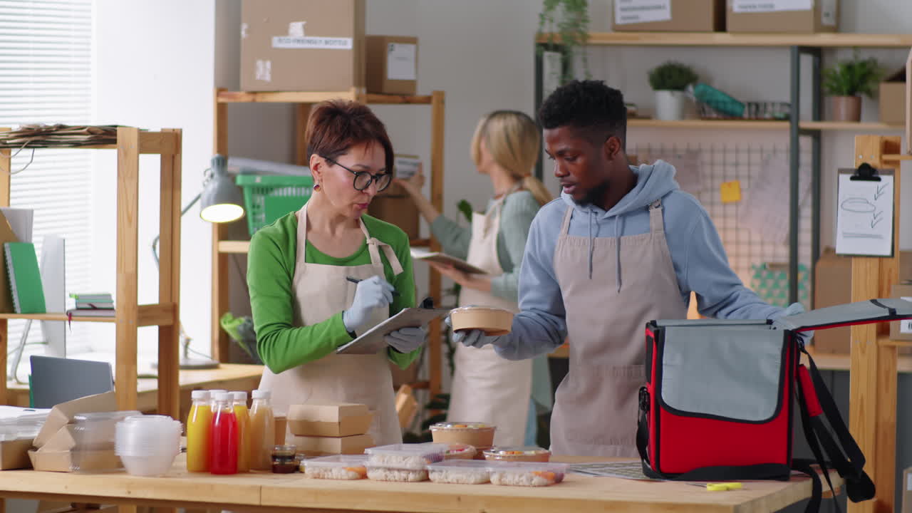 gerente multiétnico y mensajero preparando alimentos para la entrega