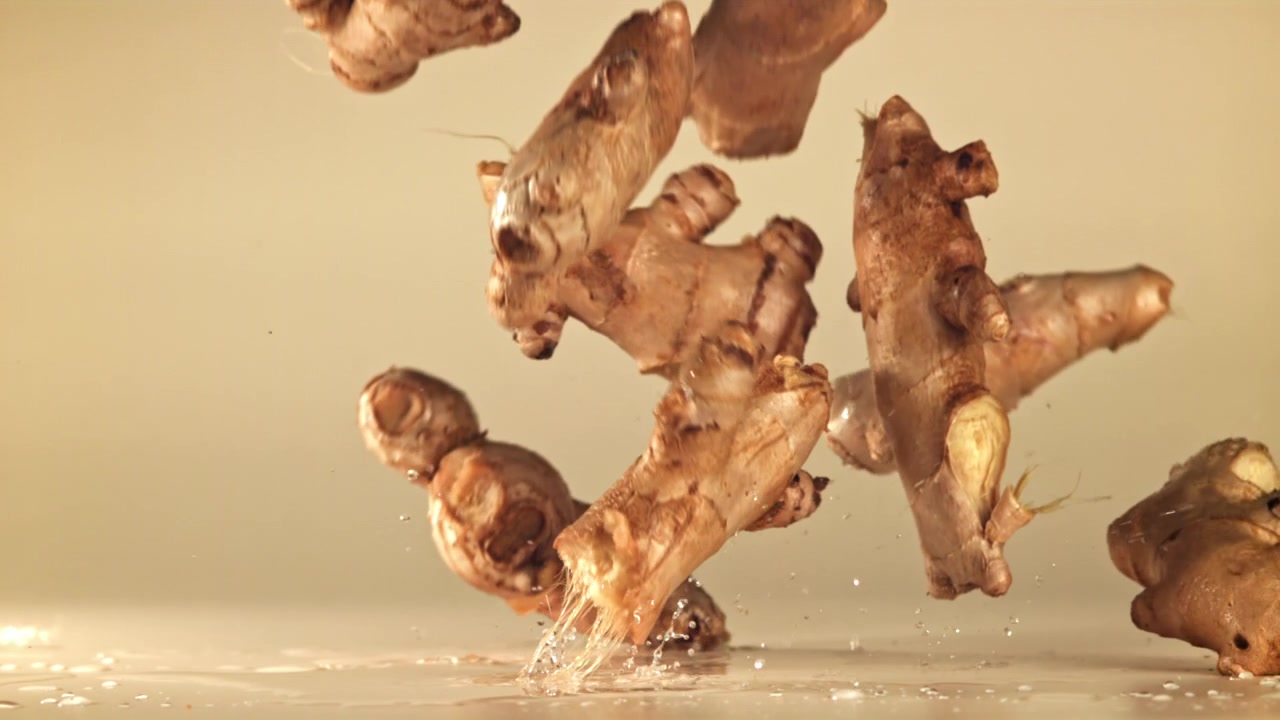 Fresh Ginger Roots Falling and Splashing Water in Slow Motion