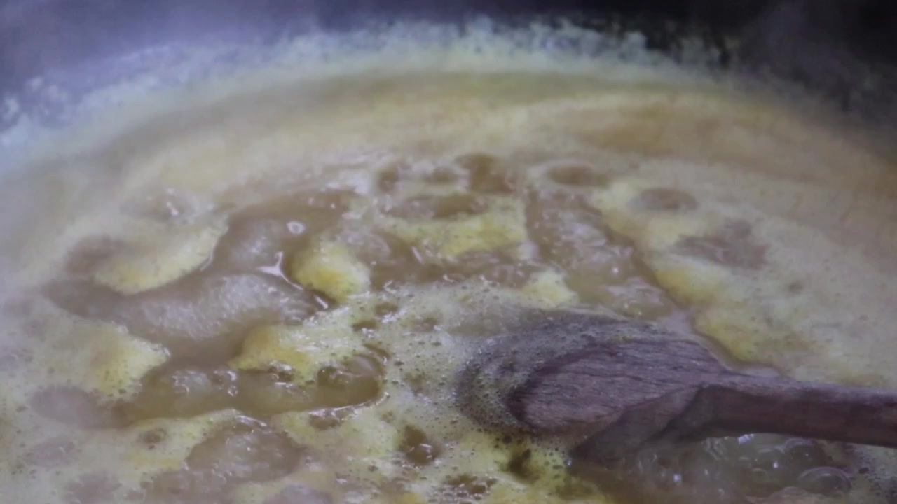 Un primo piano di marmellata di ananas bollente con una spatola di legno a lato. Ideale per temi di cucina, hobby, attività domestiche, pubblicità, cibo e commerciali.