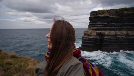 woman gazing at the majestic dun briste sea stack at downpatrick head, ireland