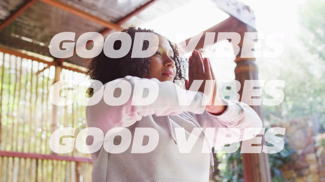 Animation of good vibes text over african american woman practicing yoga