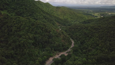 Aerial-view-of-countryside-road-passing-through-the-lush-greenery-and-foliage-tropical-rain-forest-mountain-landscape