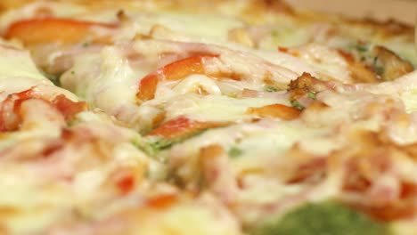 close-up of a sliced pizza with ham, tomatoes, and basil