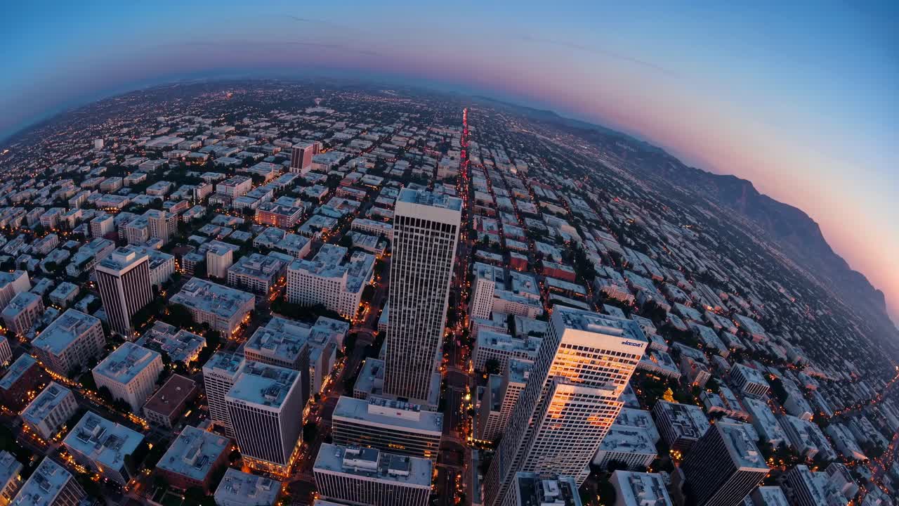 Aerial fisheye view of a cityscape at dusk, capturing skyscrapers and streets in a dynamic, curved