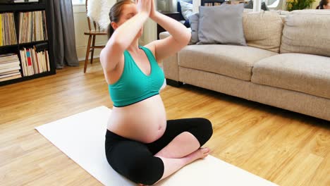 mujer embarazada practicando yoga en la sala de estar