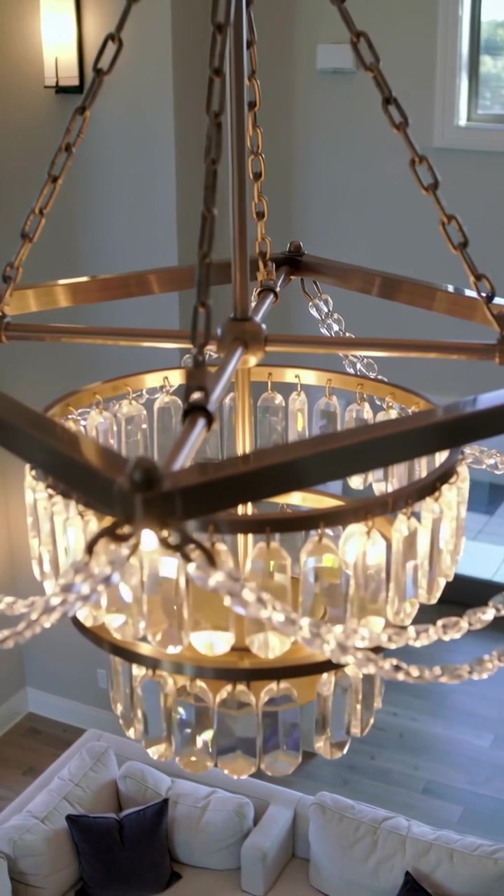 Video verticale: Telecamera in discesa che rivela un lampadario di cristallo illuminato e un divano per mostrare un atrio a due piani.