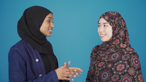 asian muslim woman and african muslim woman chatting, smiling. muslim brotherhood.