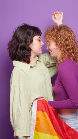lesbian couple embracing and kissing with a rainbow flag