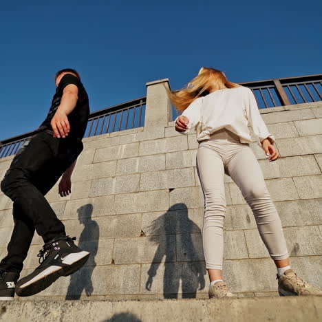 happy teens near the wall. young man in black and woman in white outdoors. slow motion. view from below.