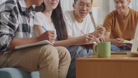 close up of asian teen group with a laptop studying at home. helping each other doing project, discussing, writing into notebook