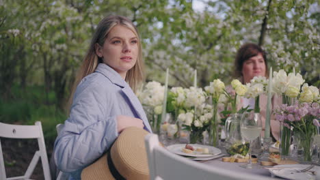 portrait of beautiful female guest of garden party lady is sitting at table with flowers decoration