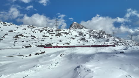 Long-red-passenger-train-on-the-Bernina-mountain-pass-on-a-sunny-winter-day