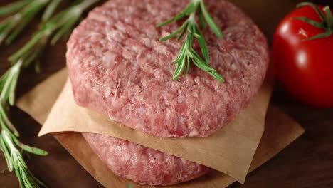 raw burger on paper with rosemary rotates.