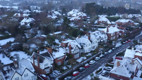 drone aerial footage of houses in england on a snowy morning with rooftops covered in snow and snow in gardens in english town