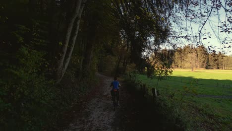 A-young-woman-cycling-with-a-touring-bike-in-a-green-forest-in-autumn-nature-in-Bavaria