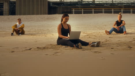 people working and relaxing on a sandy beach with an industrial background