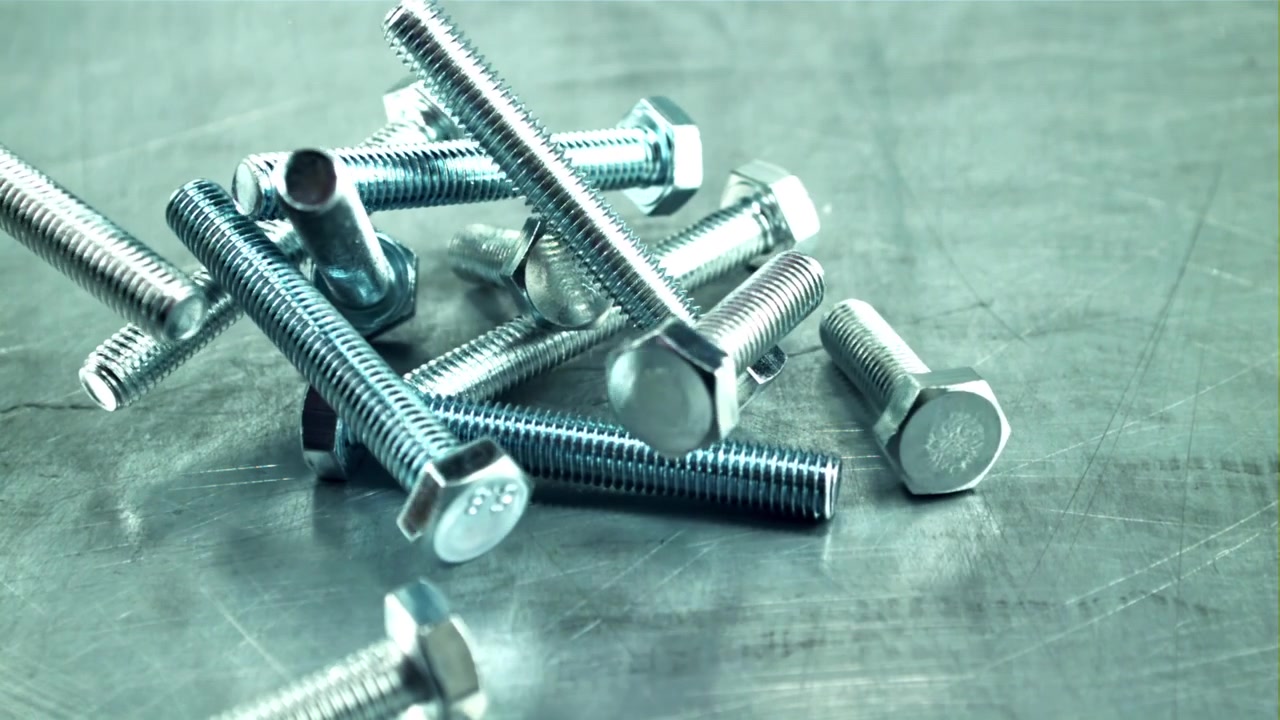 Rallentatore di bulloni metallici che cadono e si disperdono su una superficie metallica