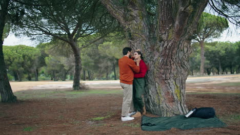 una pareja enamorada disfruta de un fin de semana en la naturaleza. turistas felices de pie abrazados cerca de un árbol.