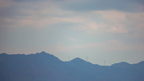 time lapse array of spinning power generating wind turbines along mountain ridge